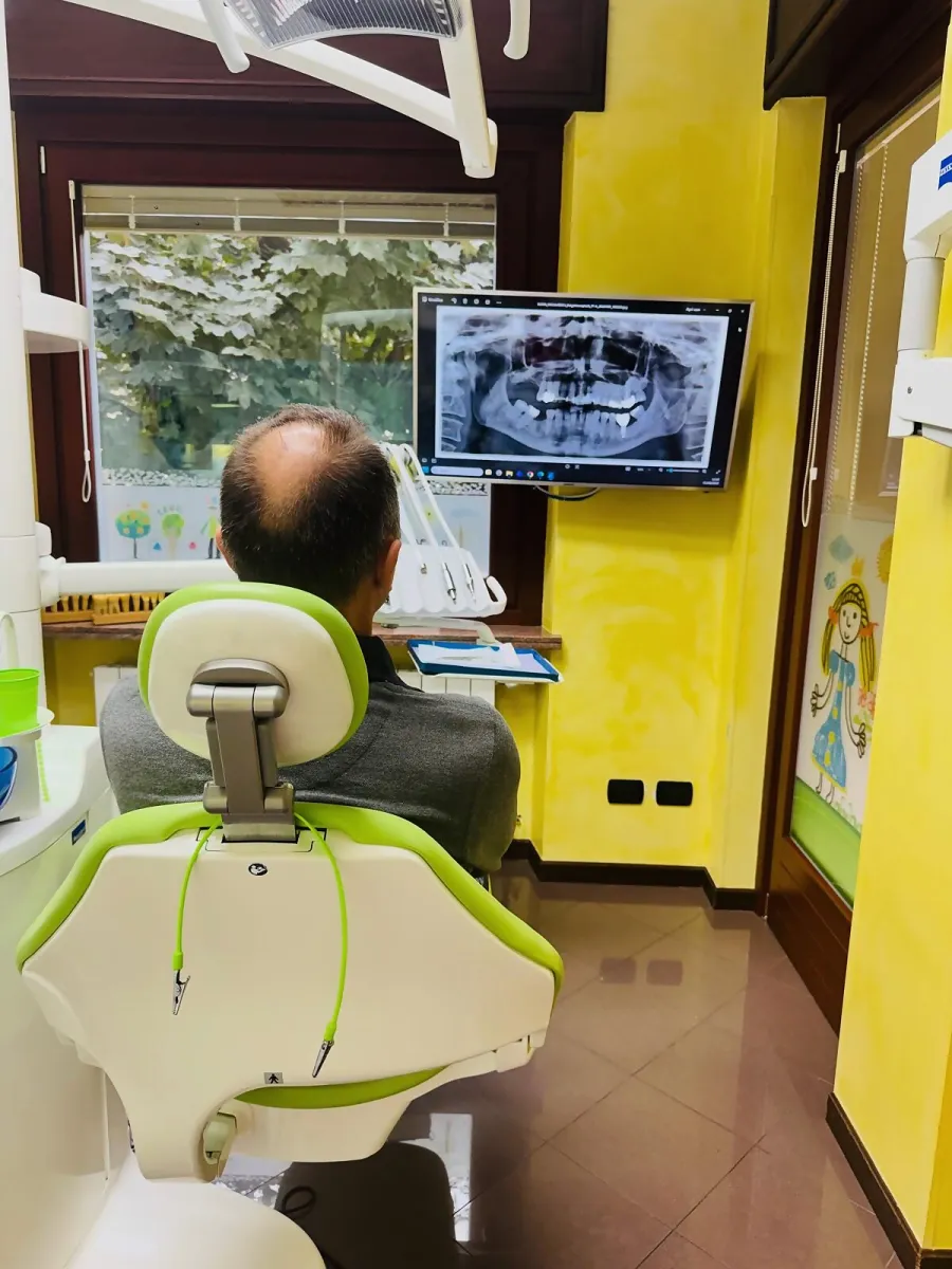 Paziente in poltrona davanti al monitor con la radiografia della bocca